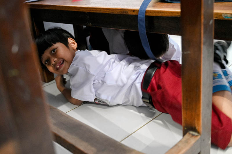 KETAKUTAN: Salah satu siswa bersembunyi di bawah meja belajar ketika mendapat giliran disuntik vaksin.