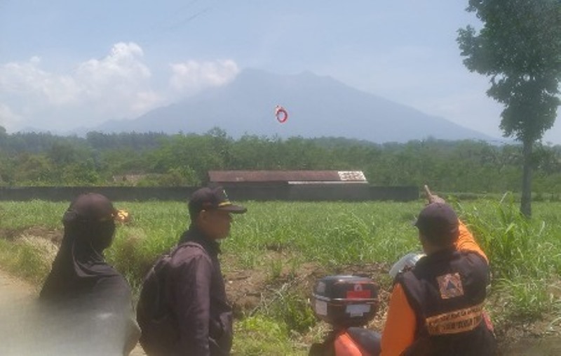SURVEI LOKASI: Ismanto (kanan) memantau asap tipis akibat munculnya titik api di Gunung Raung dari Dusun Wonorejo, Desa Kalibaru Wetan, Kcamatan Kalibaru Selasa (15/10).