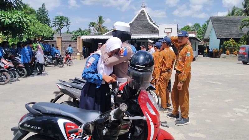 TAKUT DIHUKUM: Ipda Enita Dwi Rahayu menenangkan siswi yang menangis karena ketakutan saat terjaring razia di halaman sekolah Rabu (16/10).