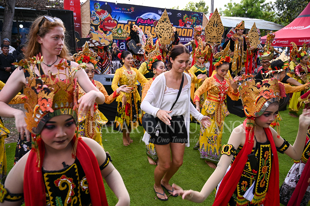 MENIKMATI: Salah satu turis mancanegara asyik menari bersama para siswa peserta Festival Padang Ulanan di Pantai Marina Boom Banyuwangi, Kamis sore (24/10).