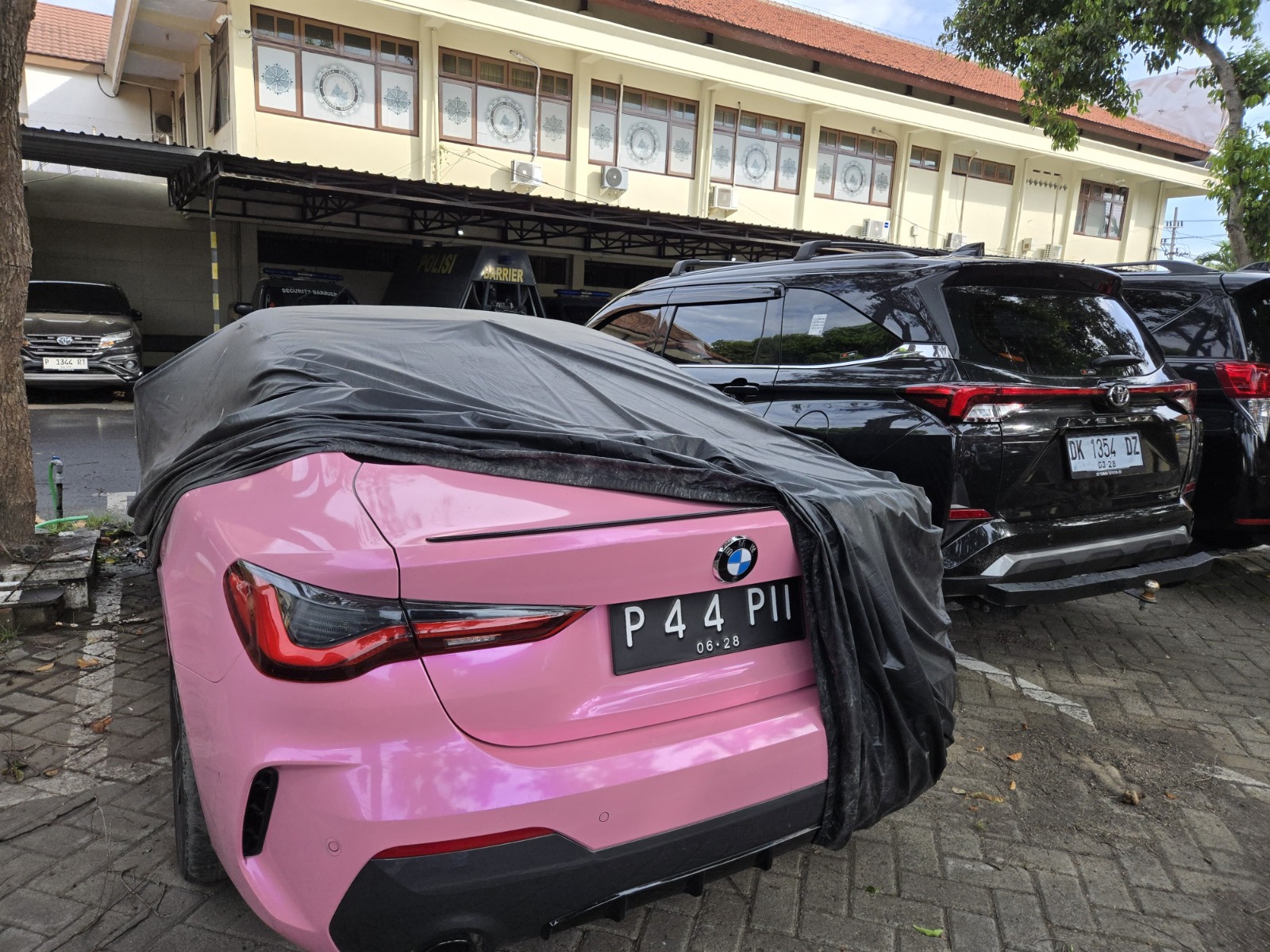 DITUTUP TERPAL: Mobil BMW bernopol P 44 PII diamankan di Polresta Banyuwangi kemarin (1/3). Mobil warna pink itu milik seorang pengusaha bernama  Muhammad Murni Abdullah.