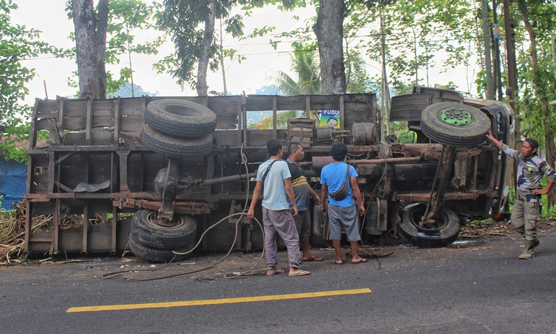 BIKIN MACET: Truk fuso bermuatan tebu terguling di jalan raya Dusun Kalikempit, Desa Tulungrejo, Kecamatan Glenmore Senin (11/11).