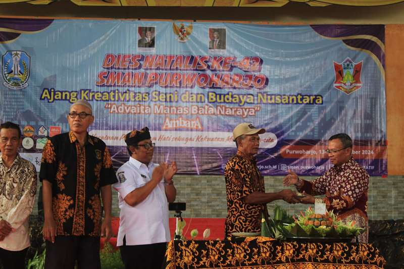 PENGHORMATAN: Kepala SMAN 1 Purwoharjo Akib Effendy menyerahkan potongan nasi tumpeng kepada guru purna dalam Dies Natalis ke-42 SMAN 1 Prwoharjo Rabu (13/11).