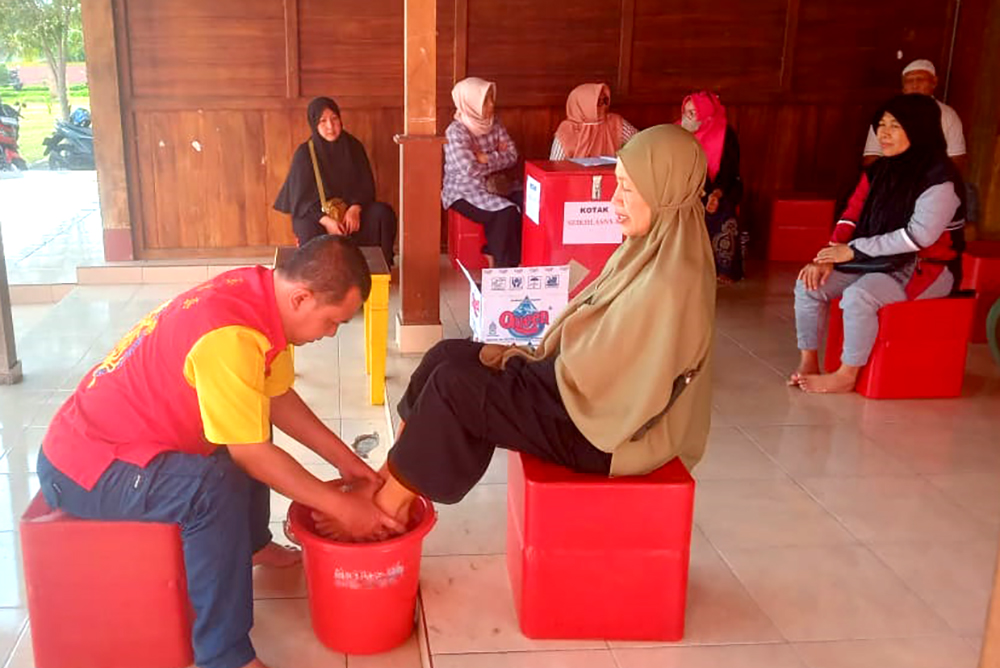 MENGOBATI: Sinshe Acong melakukan terapi rendam es kepada salah satu pasien di kompleks Masjid Haji Muhammad Cheng Hoo Banyuwangi, Jumat (15/11).