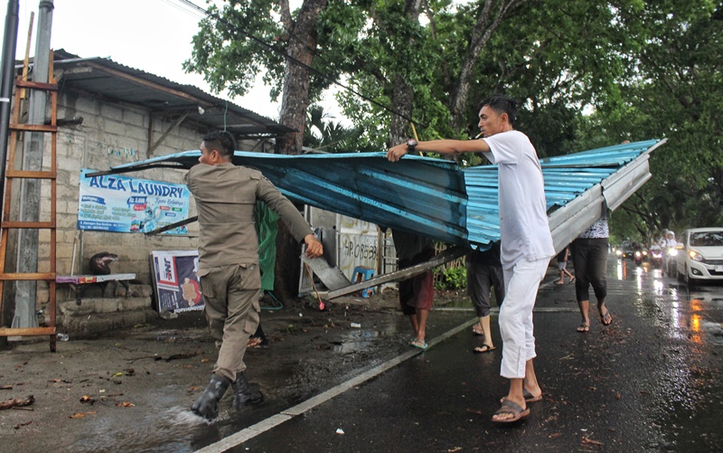 GOTONG ROYONG: Warga memindahkan atap kanopi milik Amalia Indah yang terbawa angin puting beliung di Jalan Diponegoro, Dusun Krajan 2, Desa/Kecamatan Gambiran Selasa (19/11).