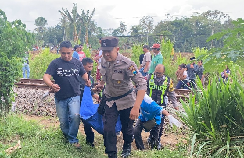 EVAKUASI: Anggota Polsek Sempu dan Polsek Genteng bersama warga mengevakuasi jenazah Umi Farida yang meninggal karena ditemper kereta api pada Senin (18/11).