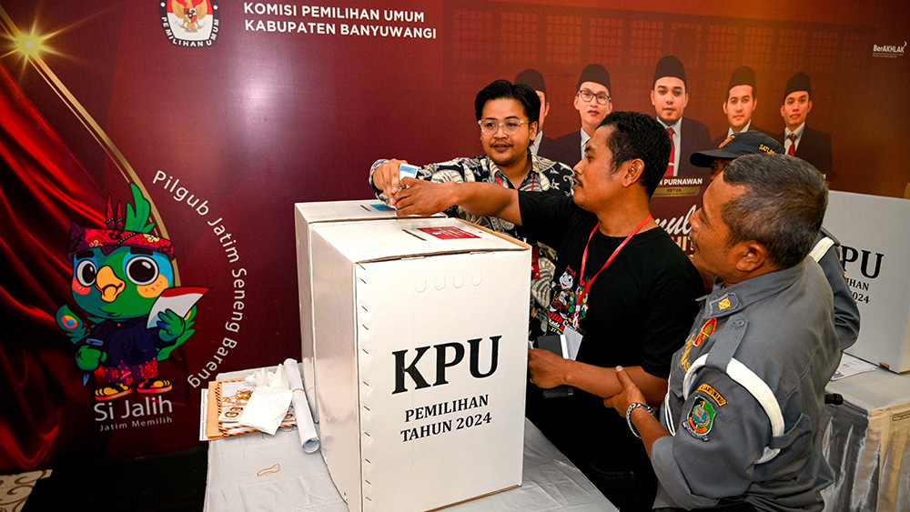 Petugas mempraktikkan tata cara pencoblosan dan lantas memasukkan surat suara ke kotak suara dalam simulasi Pilkada 2024 yang digelar KPU di aula Stikes Banyuwangi Kami
