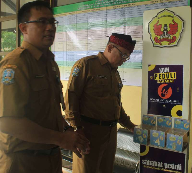 MEMASUKKAN: Kacabdispendik Jatim wilayah Banyuwangi Ahmad Jaenuri didampingi Kepala Smaring Imam Nur Samsudin melihat tempat untuk koin peduli sahabat pada Selasa (26/11).