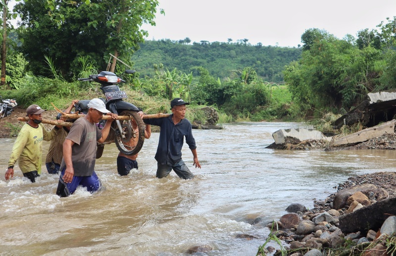 SENGSARA: Warga gotong-royong memikul sepeda motor untuk menyeberangi Kali Lele di Kampung Mbaung, Dusun Sumberurip, Desa Barurejo, Kecamatan Siliragung Minggu (15/12).