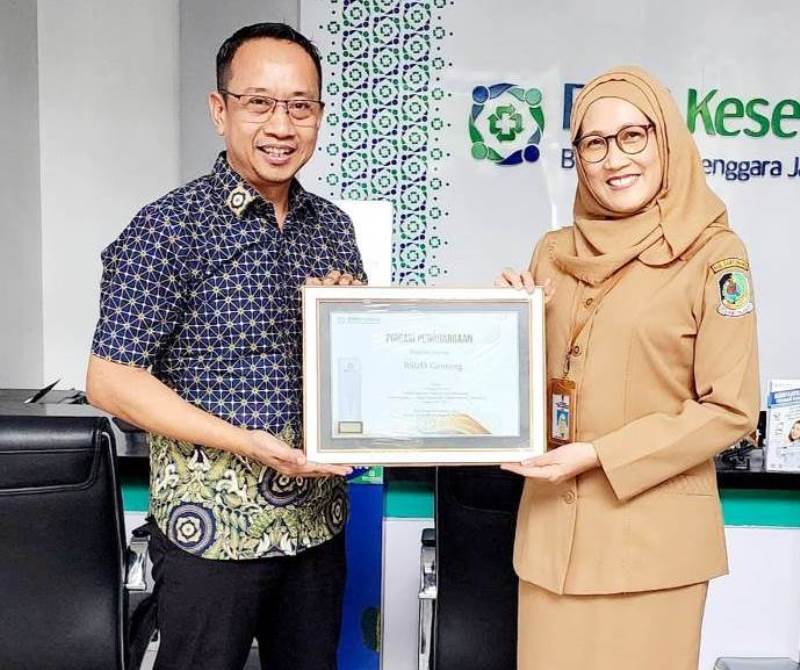PRESTASI: Kepala BPJS Kesehatan Cabang Banyuwangi Titus Sri Hardianto menyerahkan piagam penghargaan kepada Direktur RSUD Genteng dr Hj Siti Asiyah Anggraeni M MRS FISQua.