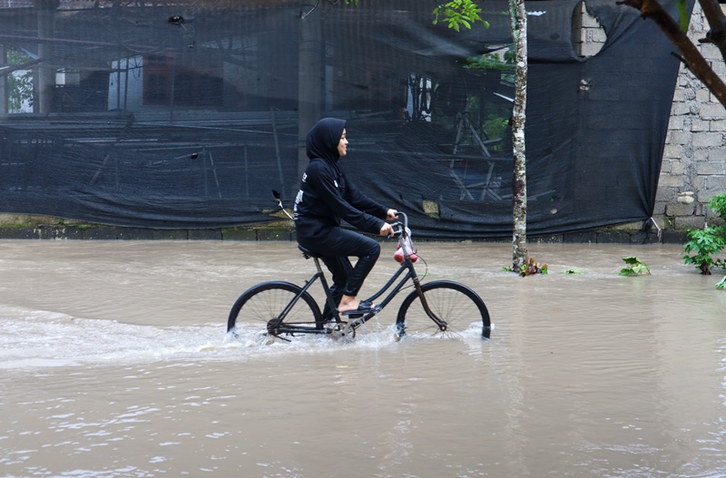 LUAPAN: Salah satu warga nekat menerabas genangan air yang muncul karena luapan Sungai Apur di Dusun Krajan, Desa/Kecamatan Siliragung Minggu (22/12).