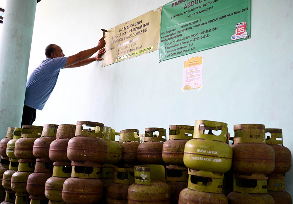 PENYESUAIAN: Warga memasang papan nama pangkalan dan harga baru elpiji tabung 3 kg di wilayah Kelurahan Kertosari, Kecamatan Banyuwangi, Selasa (14/1).