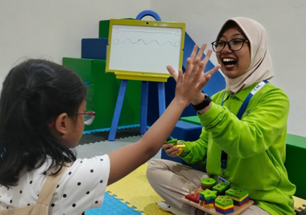 CINTA ANAK: Terapis RSU Bhakti Husada krikilan, Kecamatan Glenmore sedang menerapi salah satu anak kecandua gendet.