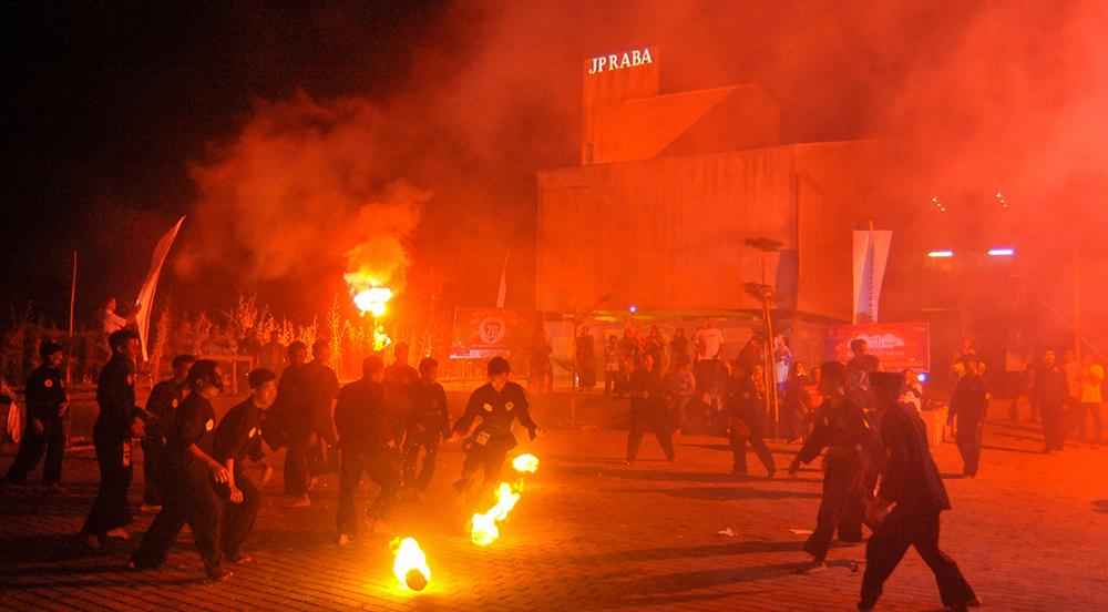 MERAH: Para remaja dan pesilat bermain sepakbola api dan menyalakan flare di halaman Grha Pena Banyuwangi tahun 2019 silam.