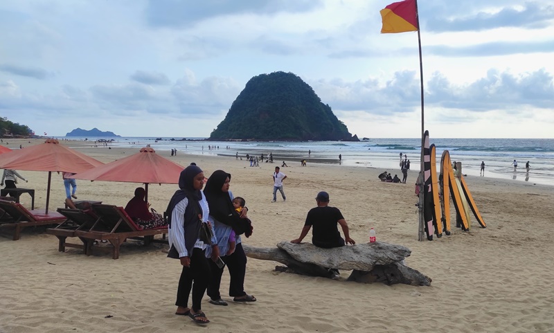 Pengunjung menikmati keindahan Pantai Pulau Merah yang ada di Dusun Pancer, Desa Sumberagung, Kecamatan Pesanggaran, Banyuwangi.