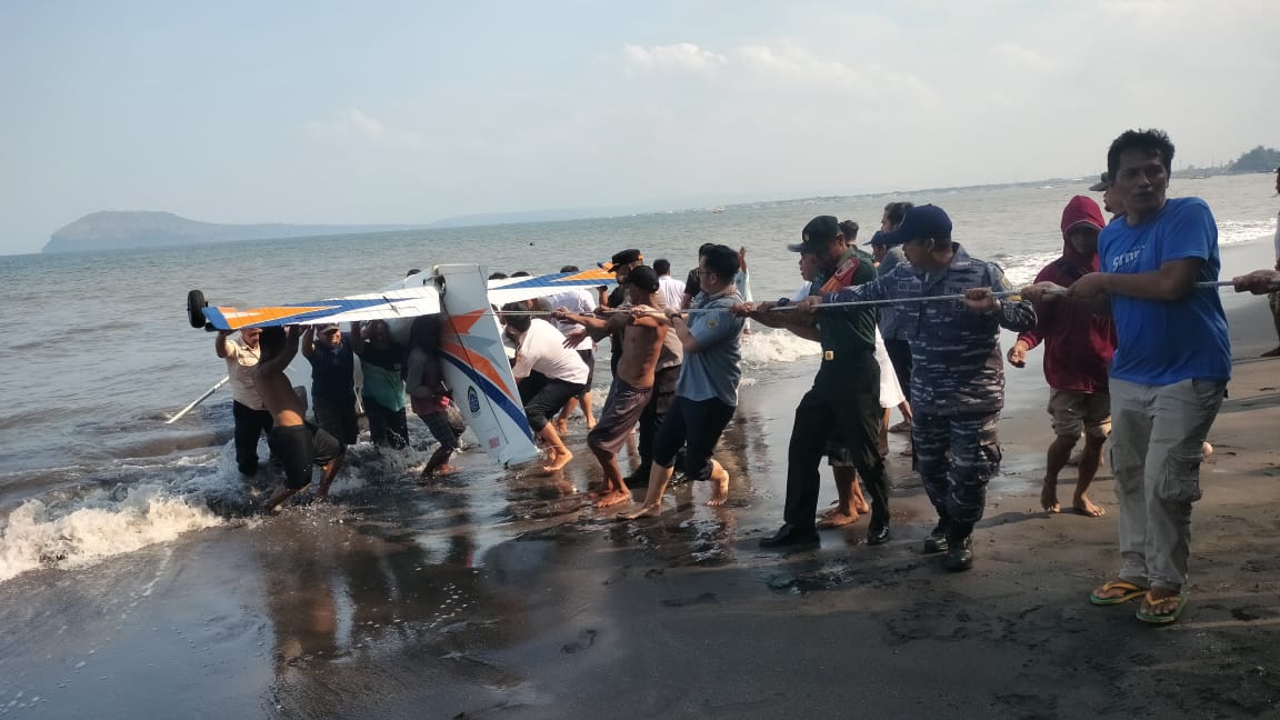 TERBALIK: Petugas bersama warga bahu-membahu menarik pesawat yang jatuh di perairan Muncar