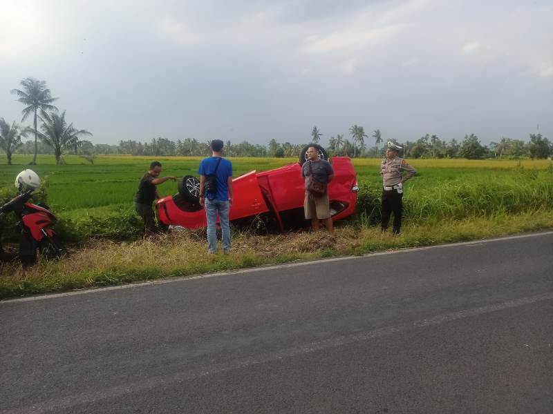 LAKA TUNGGAL: Dimas Rozil Gufron bersama anggota Unit Lantas Polsek Rogojampi dan warga sedang mengevakuasi mobil Toyota Cayla yang terbalik di pinggir Jalan Lingkar Barat, Dusun Gitik, Desa Gitik.