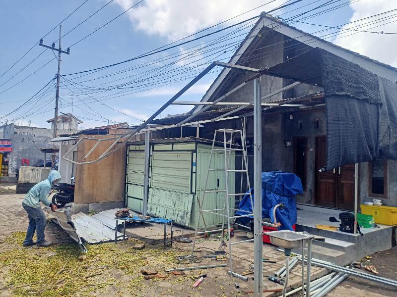 PEMBENAHAN: Proses perbaikan kedai makanan yang tertimpa pohon trembesi di Jalan Brawijaya, Dusun Krajan, Desa Kedungrejo, Kecamatan Muncar Senin (24/2).