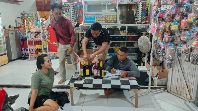 BERJEJER: Anggota Polsek Tegaldlimo saat menyita 10 botol miras di toko aksesoris Dusun Bayatrejo, Desa Wringinpitu, Kecamatan Tegaldlimo pada Jumat (28/2) malam.