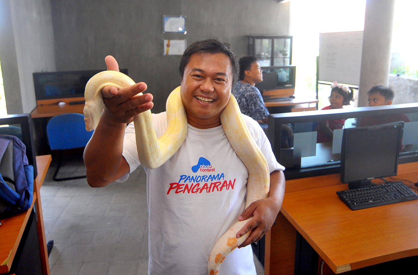 Jurnalis Radar Banyuwangi mengalungkan ular python albino di lehernya.