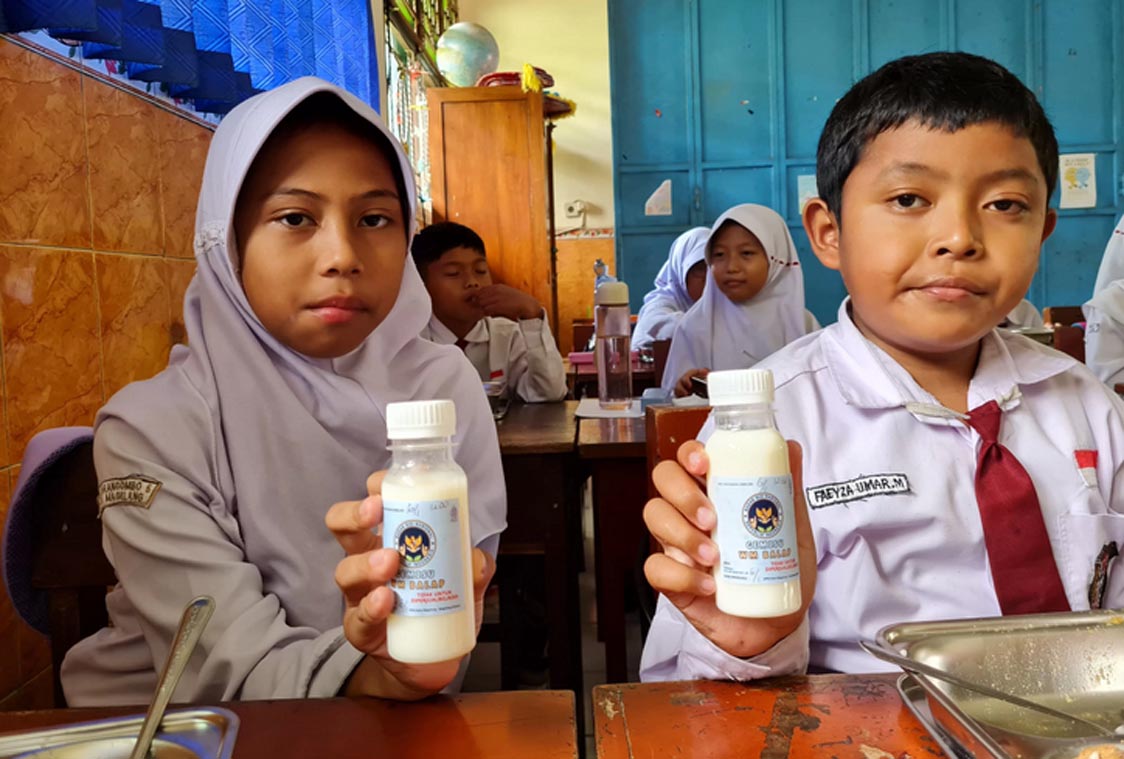 Siswa sekolah dasar di Kota Magelang menunjukkan susu murni kemasan botol untuk program MBG. (Naila Nihayah/Radar Jogja)