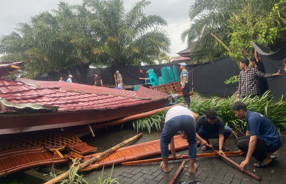 Warga membantu mengevakuasi puing-puing aula Warung Seblang di Dusun Padang Kidul, Desa Padang, Singojuruh yang ambruk diterjang angin kencang, Rabu (19/3).