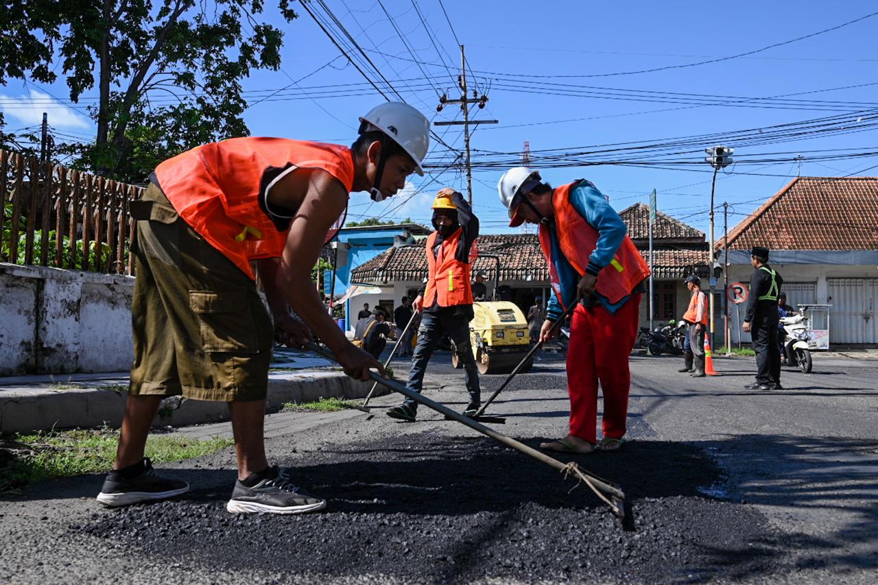 Satgas jalan berlubang menambal Jalan Surati Banyuwangi yang bolong-bolong.