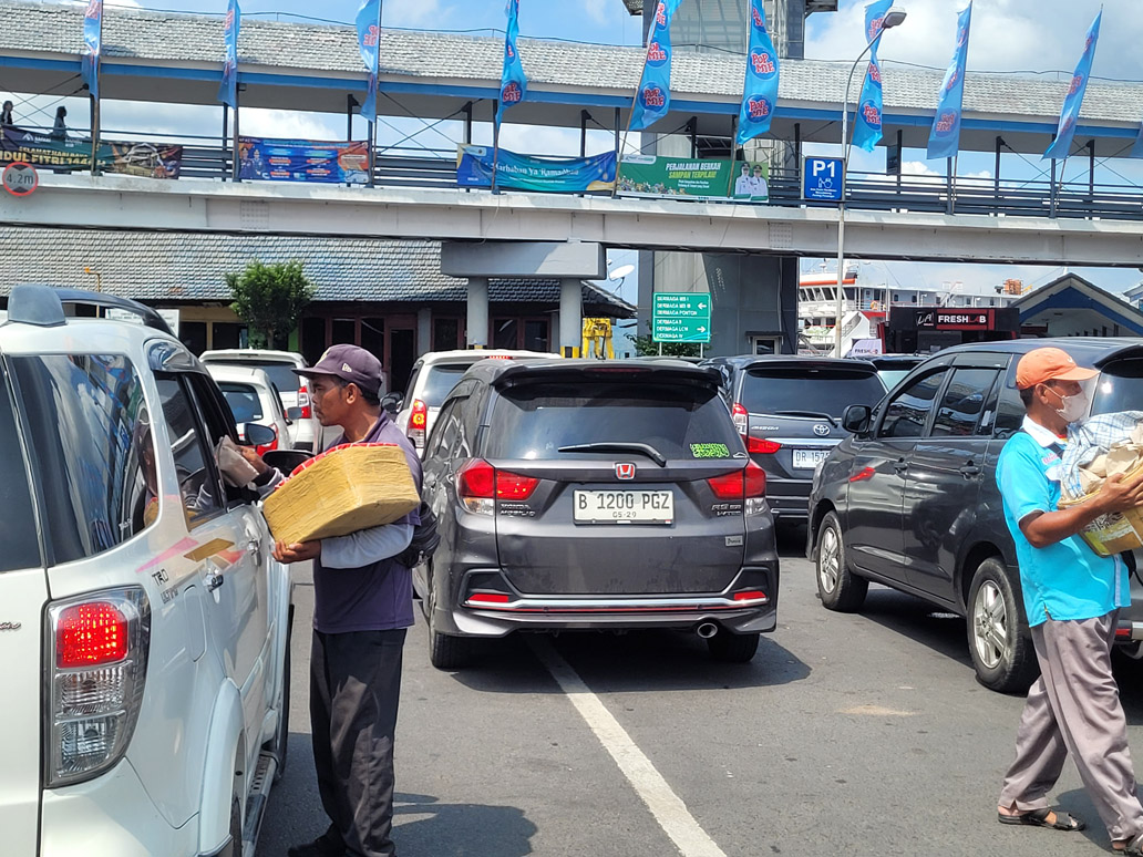 LAWAN TERIK: Pedagang nasi bungkus menjajakan dagangan saat arus balik Lebaran di Pelabuhan ASDP Ketapang, Banyuwangi, Minggu (6/4).