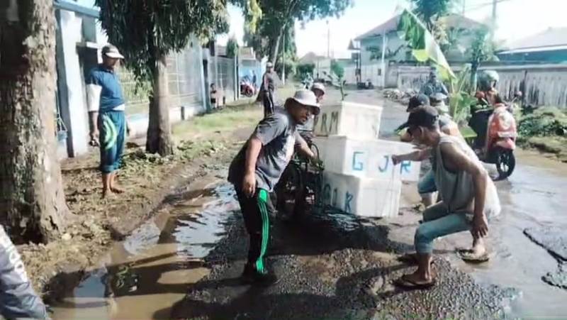 JALAN RUSAK: Warga menolong becak pengangkut ikan yang nyaris kecelakaan saat melintasi jalan rusak di Dusun Sampangan, Desa Kedungrejo, Kecamatan Muncar Minggu (13/4).