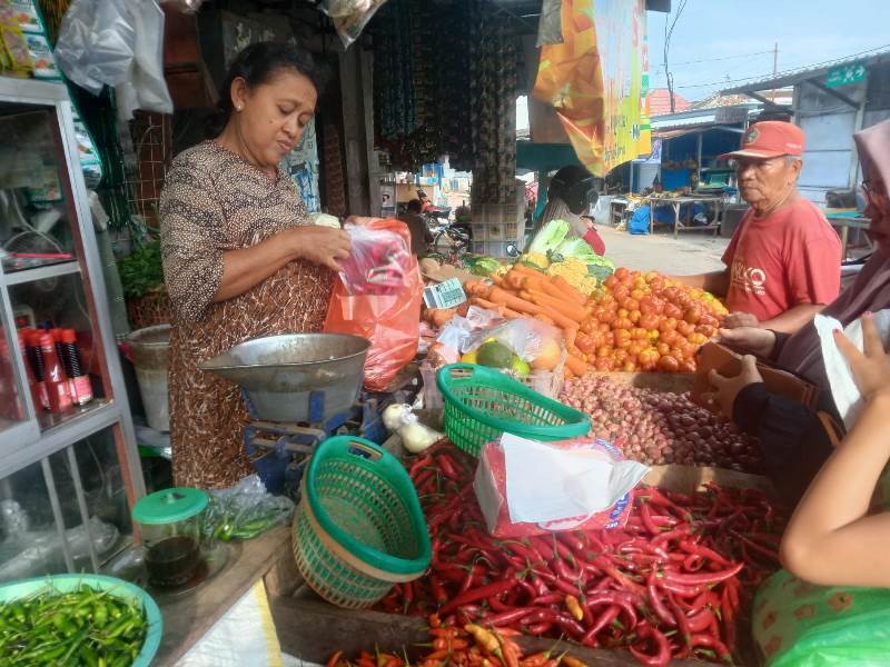 MENJAJAKAN: Penjual Bahan Dapur di Pasar Rogojampi, Niatin melayani pembeli di lapaknya Senin (14/4).