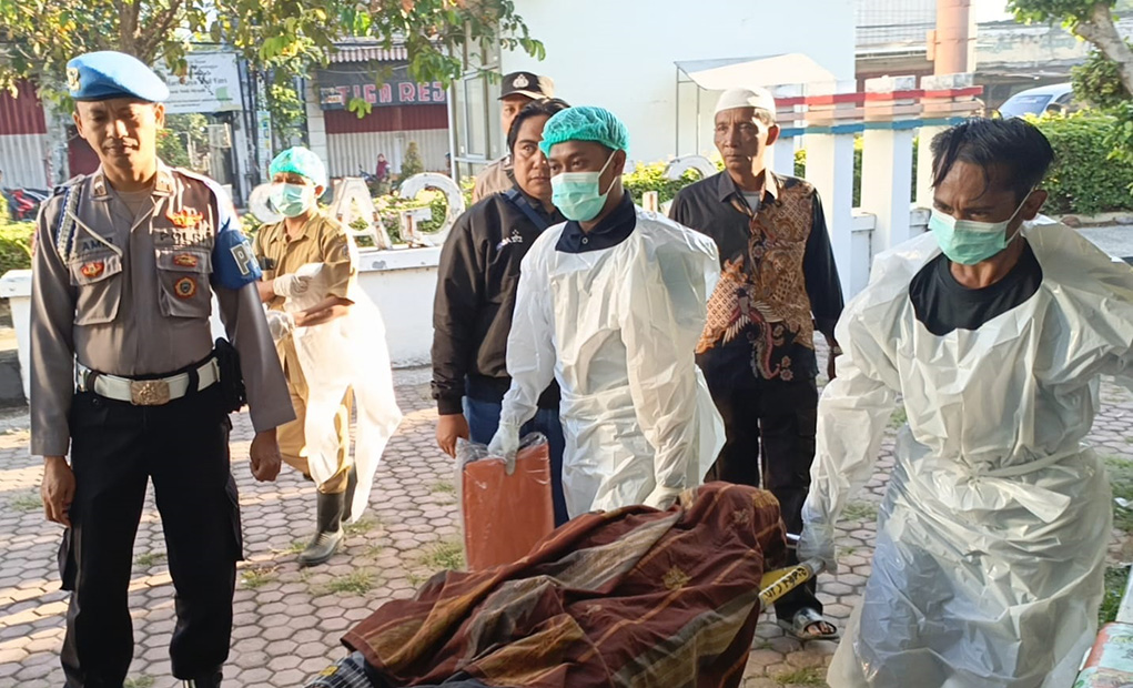 PENEMUAN MAYAT: Tim medis dan anggota Polsek Asembagus mengevakuasi jenazah Mulyadi, 51, di teras gudang genset taman kota Asembagus, Selasa (22/4).