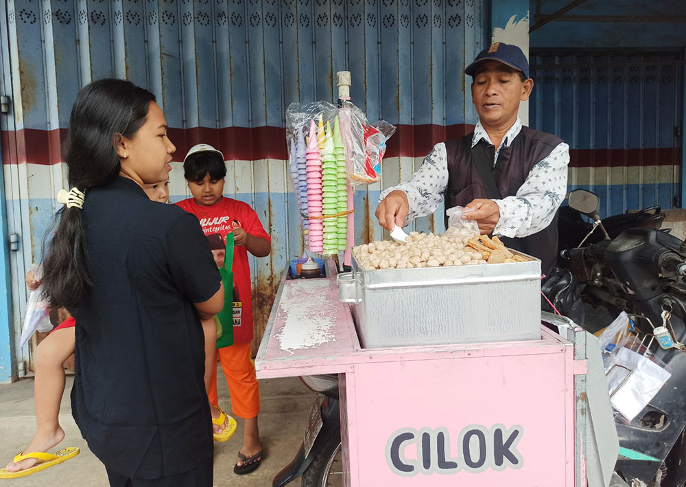 BERKAH RAMADAN: Rojali sedang melayani pembeli cilok dagangannya di kawasan Pasar Kampung Baru, Desa Jambewangi, Kecamatan Sempu.