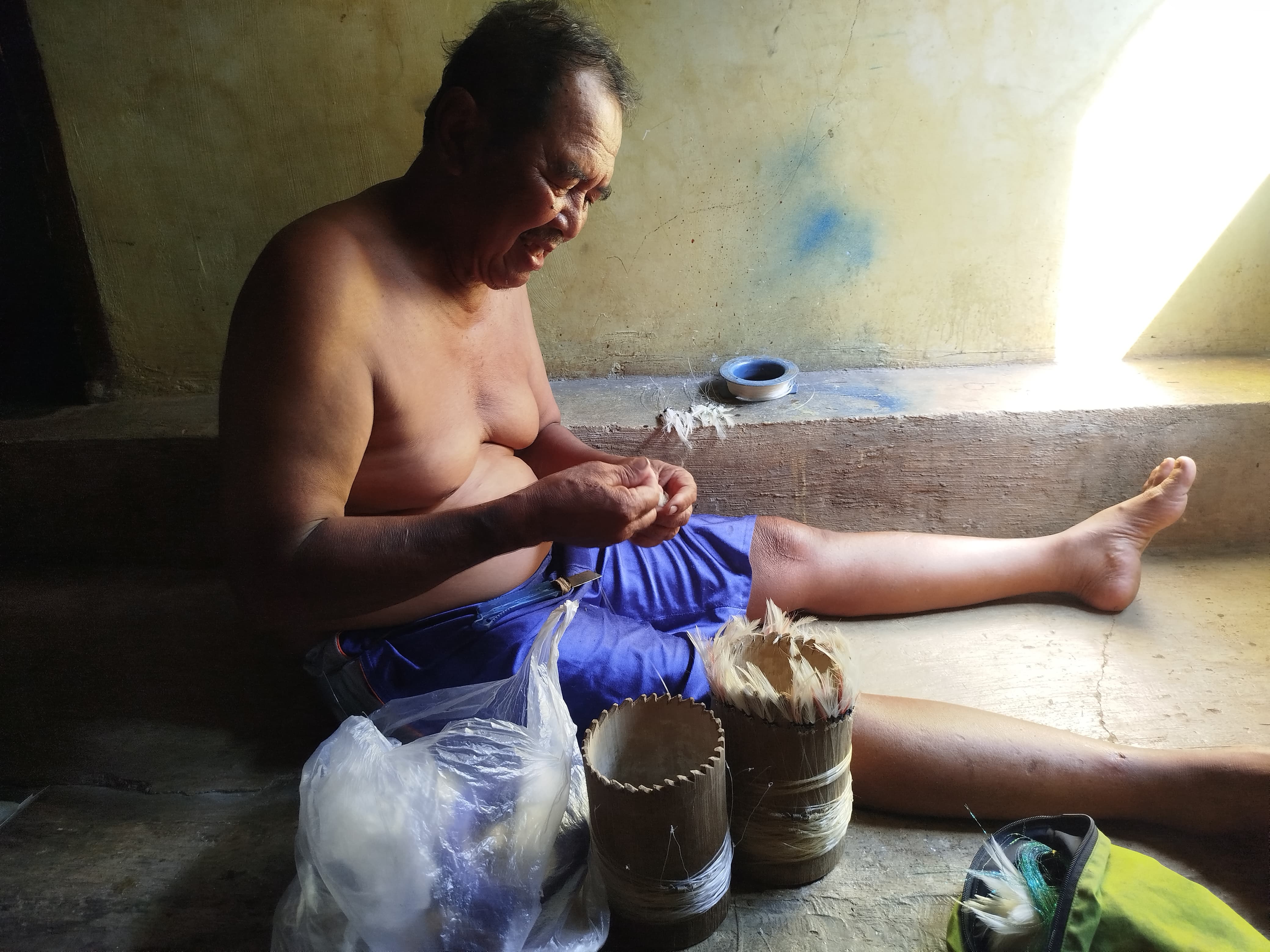 Nelayan mempersiapkan umpan pancing.