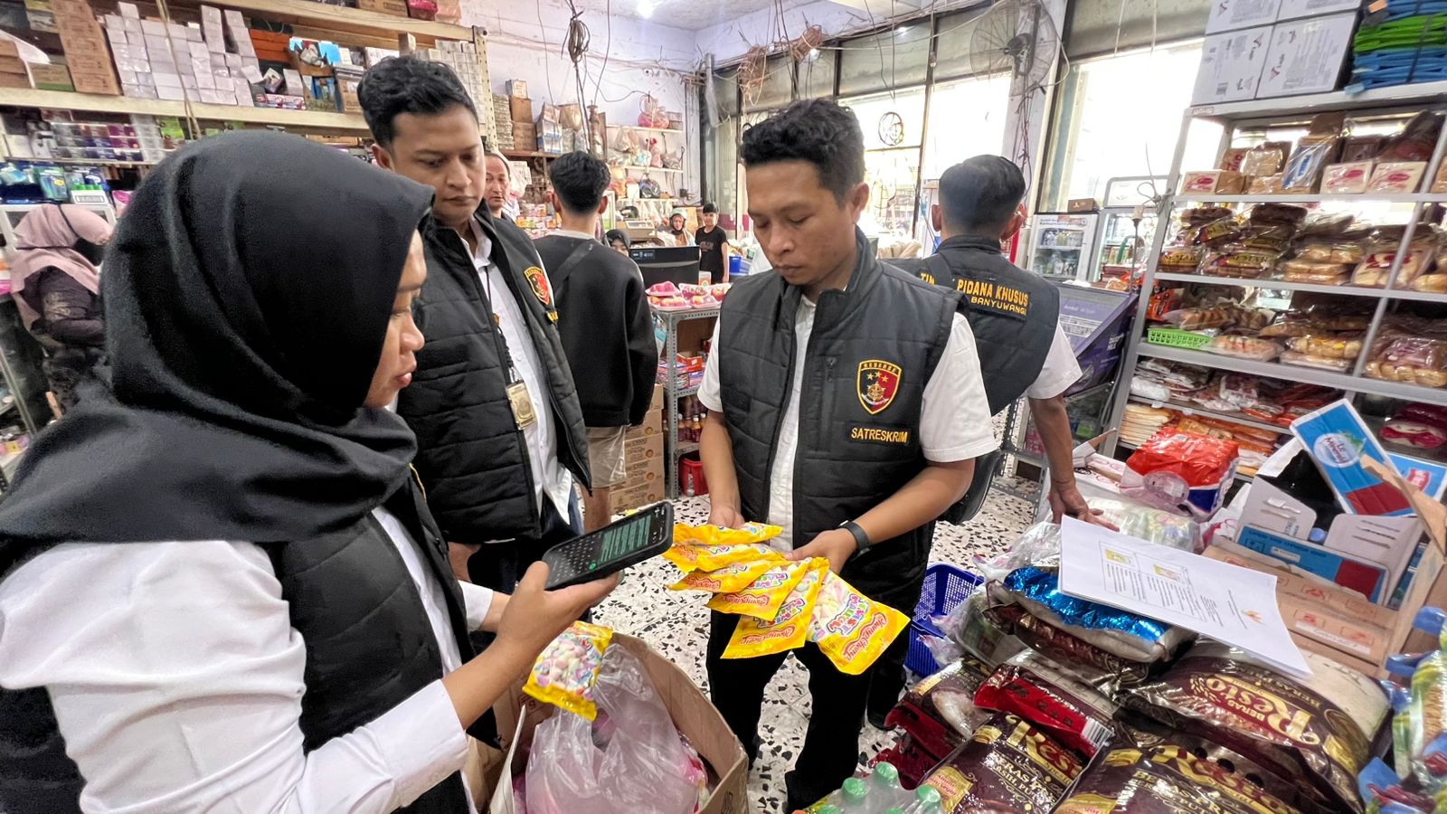 SIDAK: Satgas Pangan yang beranggotakan anggota Reskrim, Dinkes, dan Diskop-UMP memeriksa sejumlah snack kemasan di salah satu toko di Banyuwangi Senin (5/5).