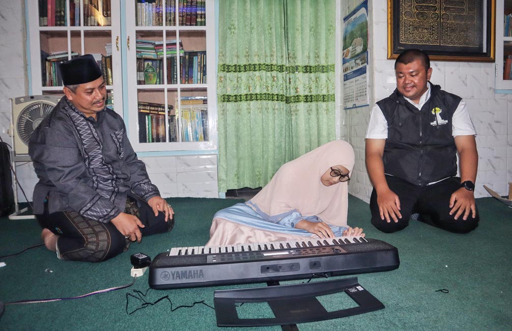 Ketua Umum BPC HIPMI Banyuwangi Ferdy Elfian (kanan) menyerahkan hadiah alat musik kibor kepada Yasmin Najma Falihah (tengah) didampingi ayahnya, KH Muhammad Nur Khotib, Selasa (6/5).