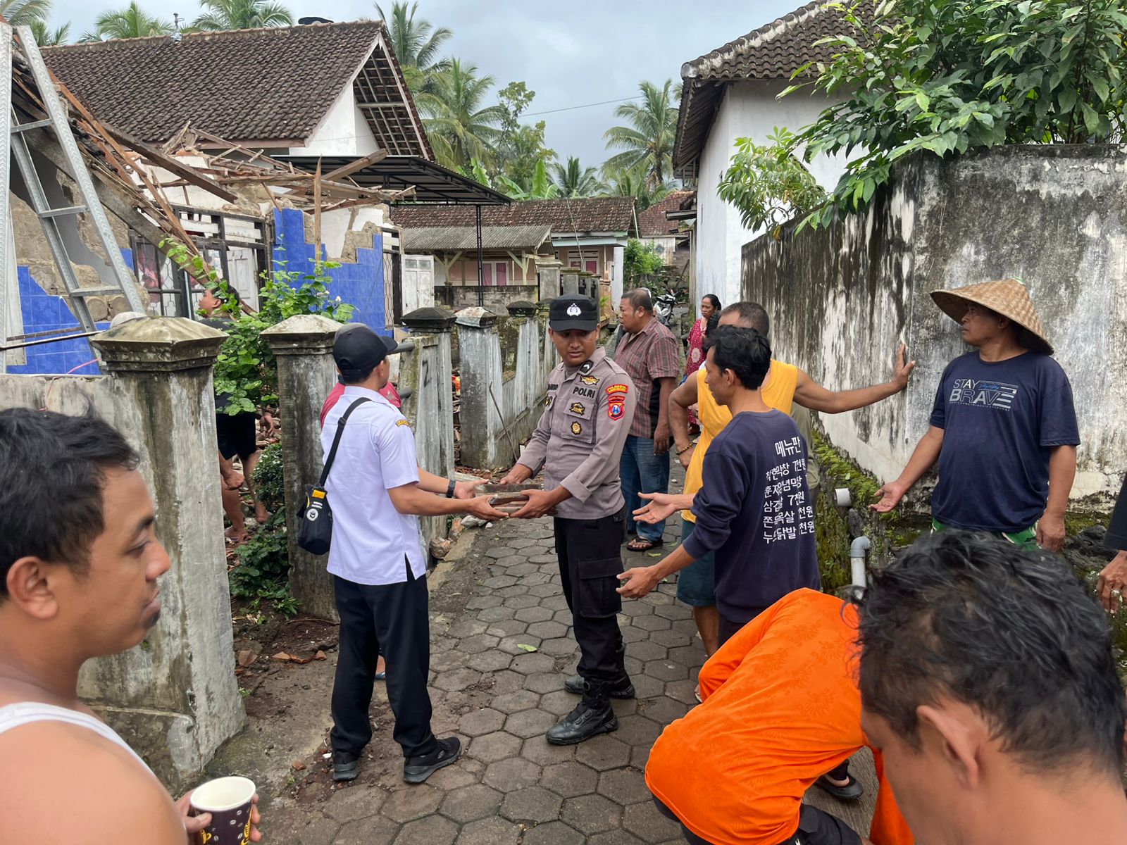 Warga dan polisi membersihkan puing rumah roboh di Songgon Banyuwangi, Rabu (7/5). (Humas Polresta Banyuwangi)