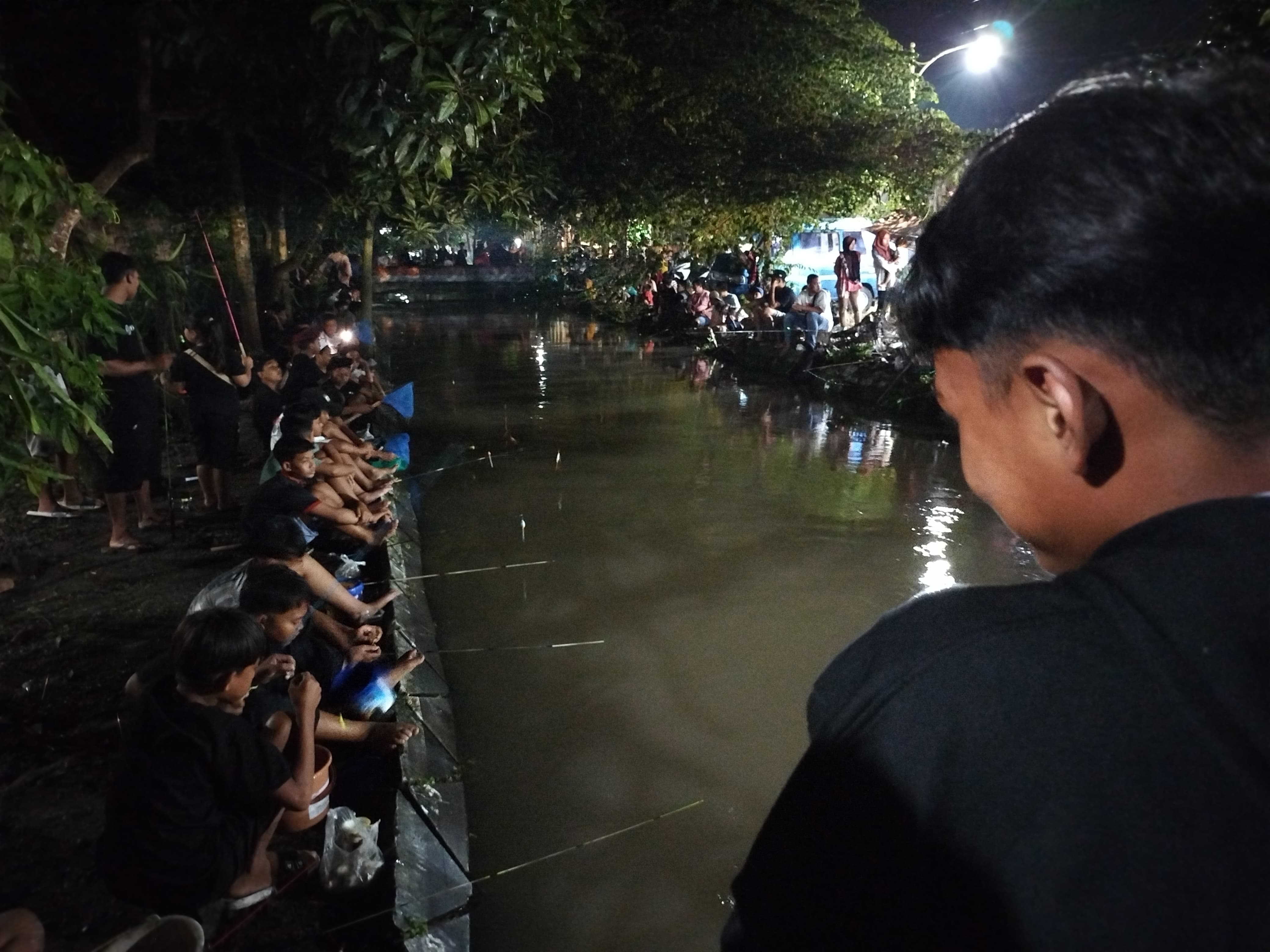 Warga Curahjati berlomba-lomba mendapatkan ikan lele di sungai.