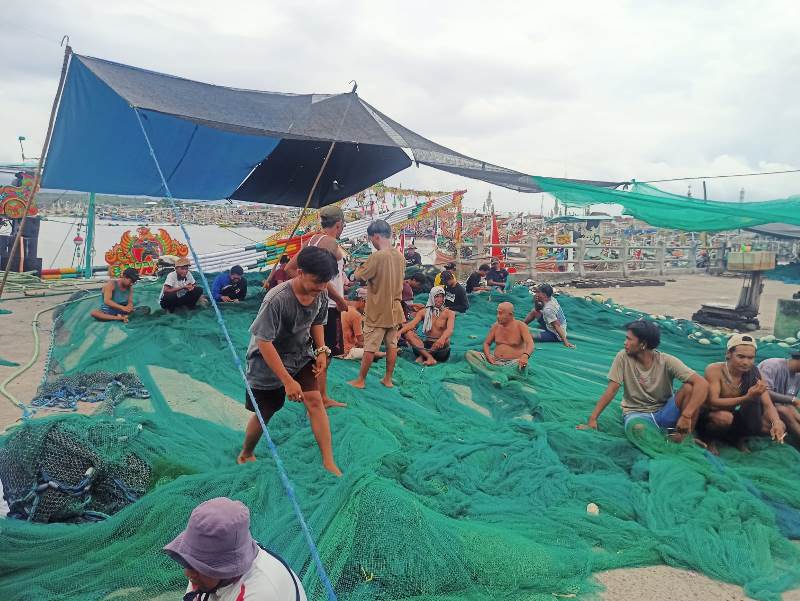 LIBUR: Para nelayan memperbaiki jaring di Pelabuhan Muncar, Desa Kedungrejo, Kecamatan Muncar Selasa (13/5).