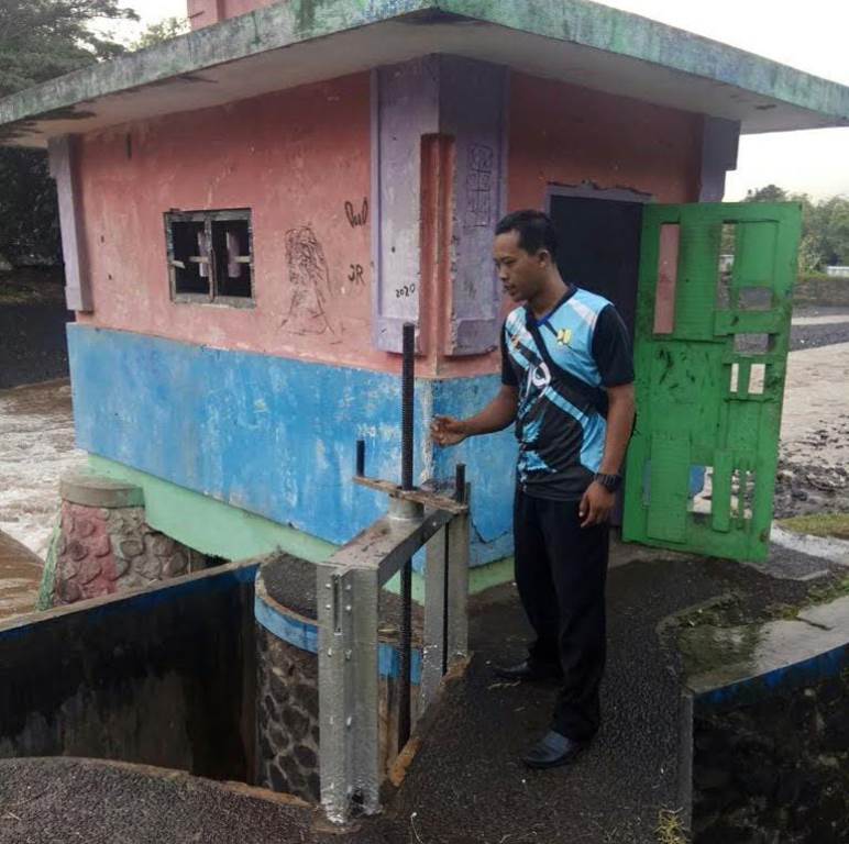 GERAK CEPAT: Petugas membuka pintu air di Dam Garit Desa Alasmalang, Kecamatan Singojuruh yang airnya mulai naik Minggu (18/5).