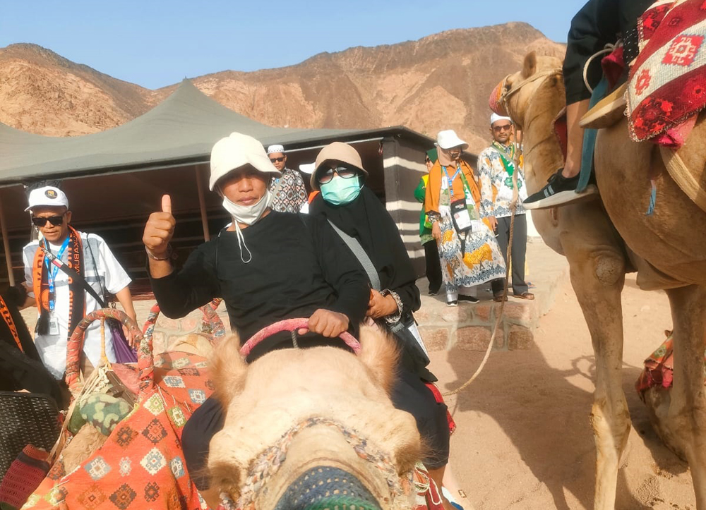 HIBURAN: Guntur Al Badri dari kloter 43 naik unta bersama istrinya di sekitar Jabal Magnet Madinah kemarin (19/5).