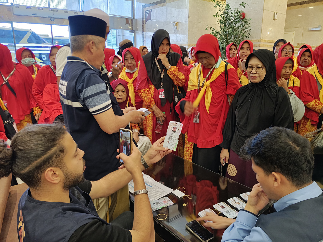 Ketua Kloter 44 Abdul Wahid (berdiri) didampingi petugas Syarikah mendistribusikan kartu nusuk di lobi Hotel Dar Al Eiman, Madinah, Senin (19/5).