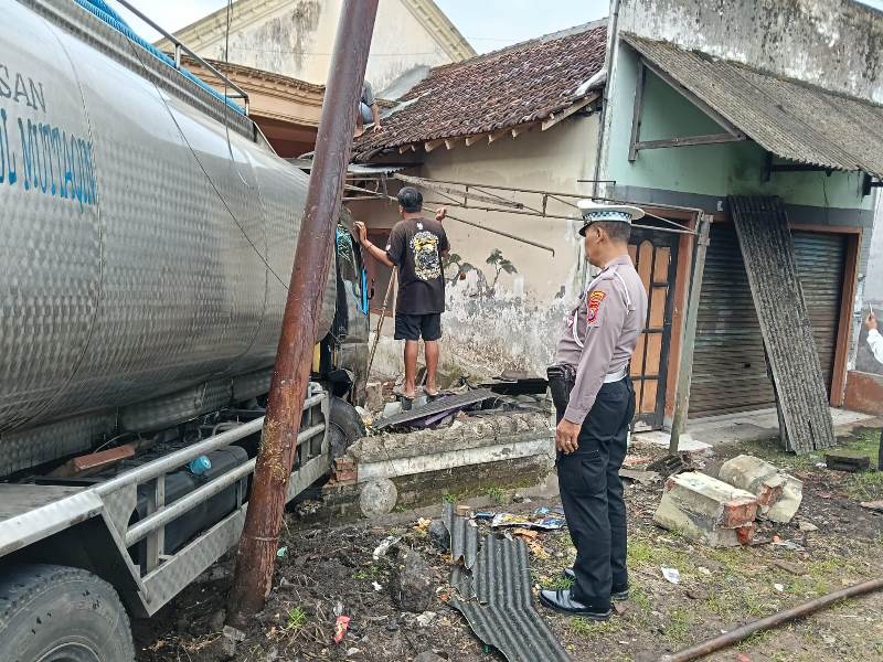 IDENTIFIKASI: Anggota Lantas Polsek Gambiran melakukan olah TKP di lokasi truk tangki air isi ulang yang menabrak pagar rumah warga Senin (19/5).