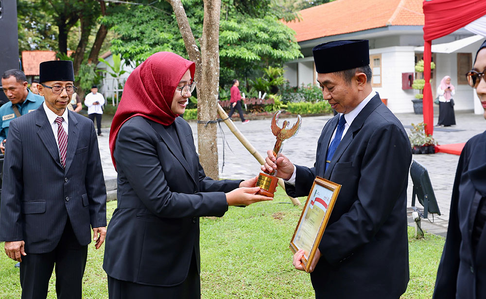 Bupati Ipuk Fiestiandani menyerahkan piala dan sertifikat ASN Berprestasi kepada Kepala Dispendik Suratno di halaman kantor Pemkab Banyuwangi, Selasa (20/5).