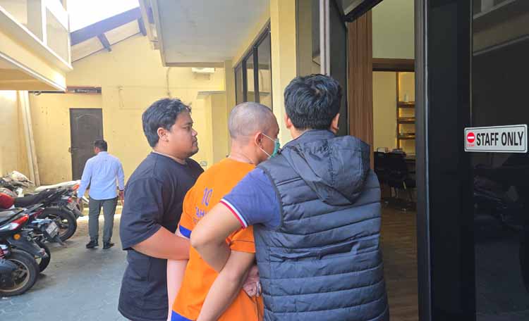 Tersangka Idrus Efendi digiring Kanit Pidsus Ipda Azmal Rahadian menuju ruang penyidik Satreskrim Polresta Banyuwangi, Sabtu (24/5) lalu.