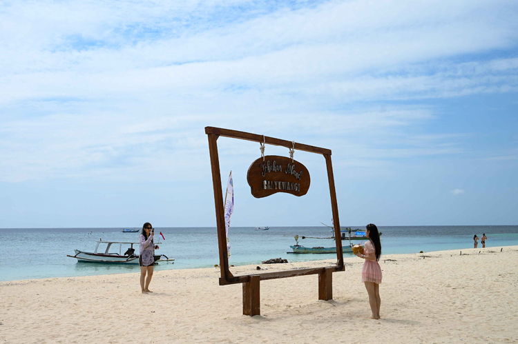 PUNYA DAYA TARIK: Rombongan wisatawan dari Tiongkok menikmati keindahan pantai Pulau Tabuhan yang memiliki pasir putih tersebut.