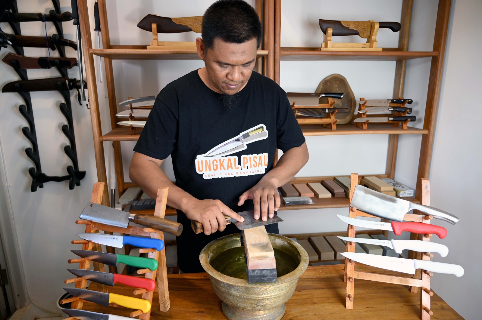 Pandu mengasah pisau tumpul di rumahnya Perumahan Kebalenan Baru I, Banyuwangi. Kehalian mengasah pisau didapat dari belajar di YouTube.