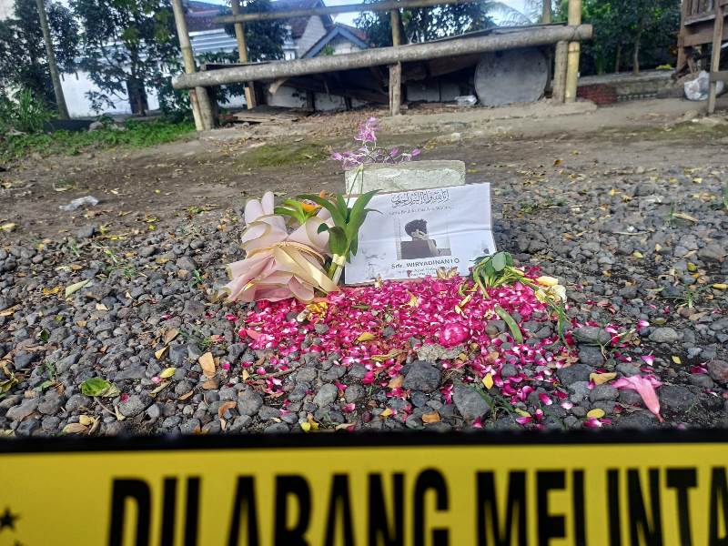 TKP: Di lokasi penganiayaan di pinggir jalan raya Dusun Gembolo, Desa Purwodadi, Kecamatan Gambiran ada batu bata putih, foto korban yang ditaburi bunga, dan ucapan belasungkawa Selasa (3/5).