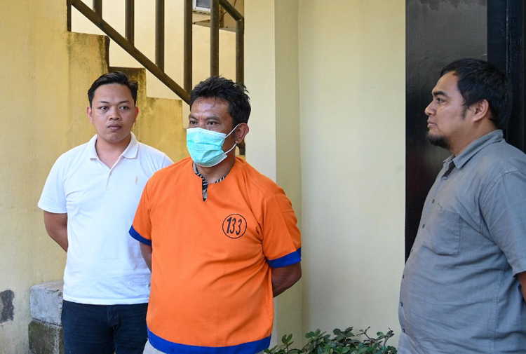 Joko Suyoto (tengah) digiring penyidik Reskrim Polresta Banyuwangi dalam rilis pengungkapan judi online di Mapolresta Banyuwangi, Rabu sore (11/6).