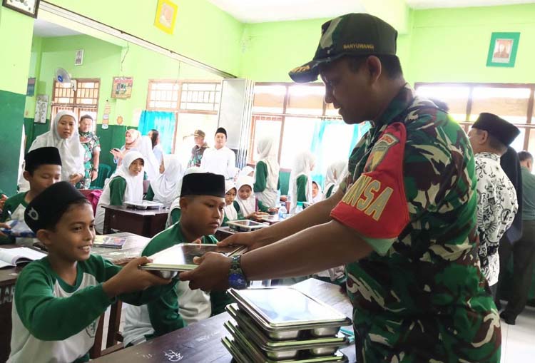 Personel TNI membagikan menu MBG untuk pelajar di Banyuwangi, Selasa (10/6).