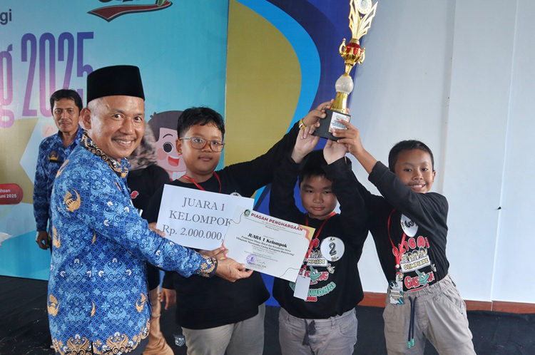 Kabid Pendidikan SD Drs Sutikno MPd menyerahkan penghargaan kepada juara Olimpiade Gasing 2025 dari Kecamatan Genteng, Selasa (17/6).